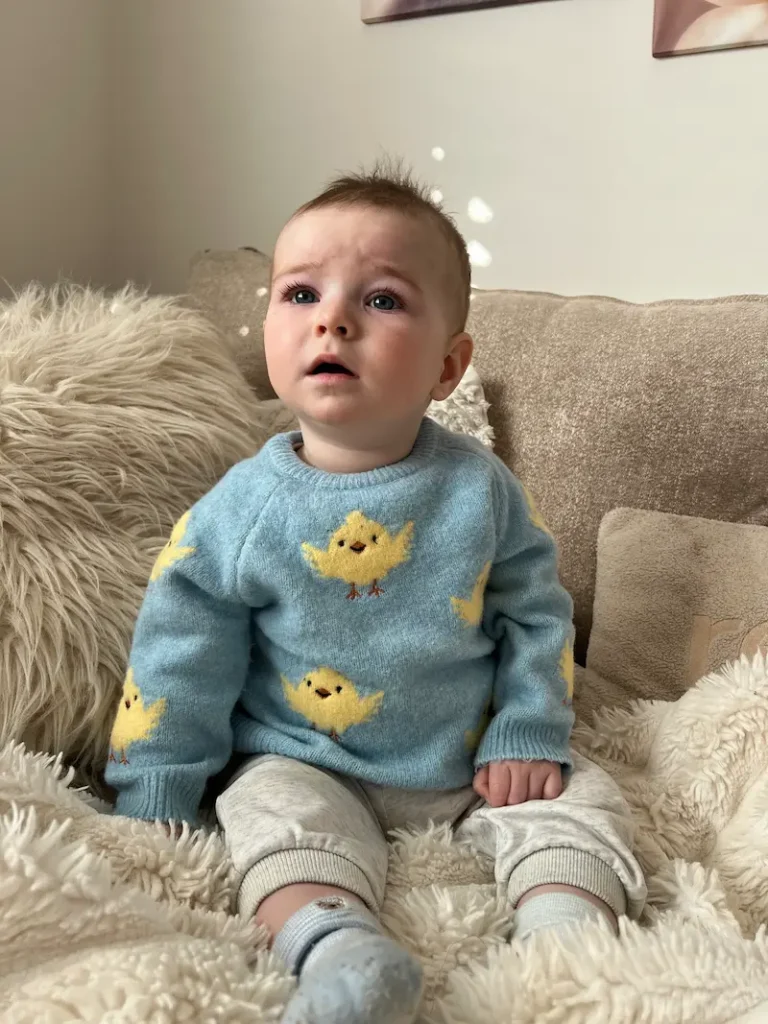 baby boy in blue jumper sat on sofa